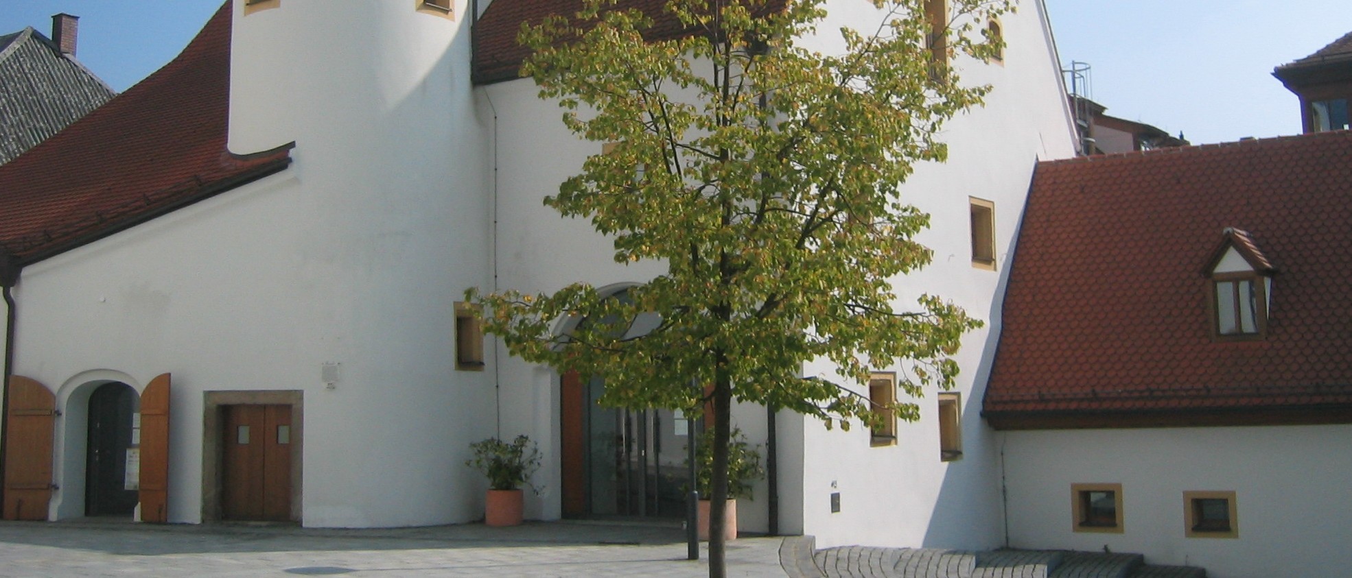 Das Foto ist Teil einer Slideshow. Stadtmuseum von außen. Blick auf Erd- und Mittelgeschoß, die Eingänge und das Nebengebäude im Anschnitt.