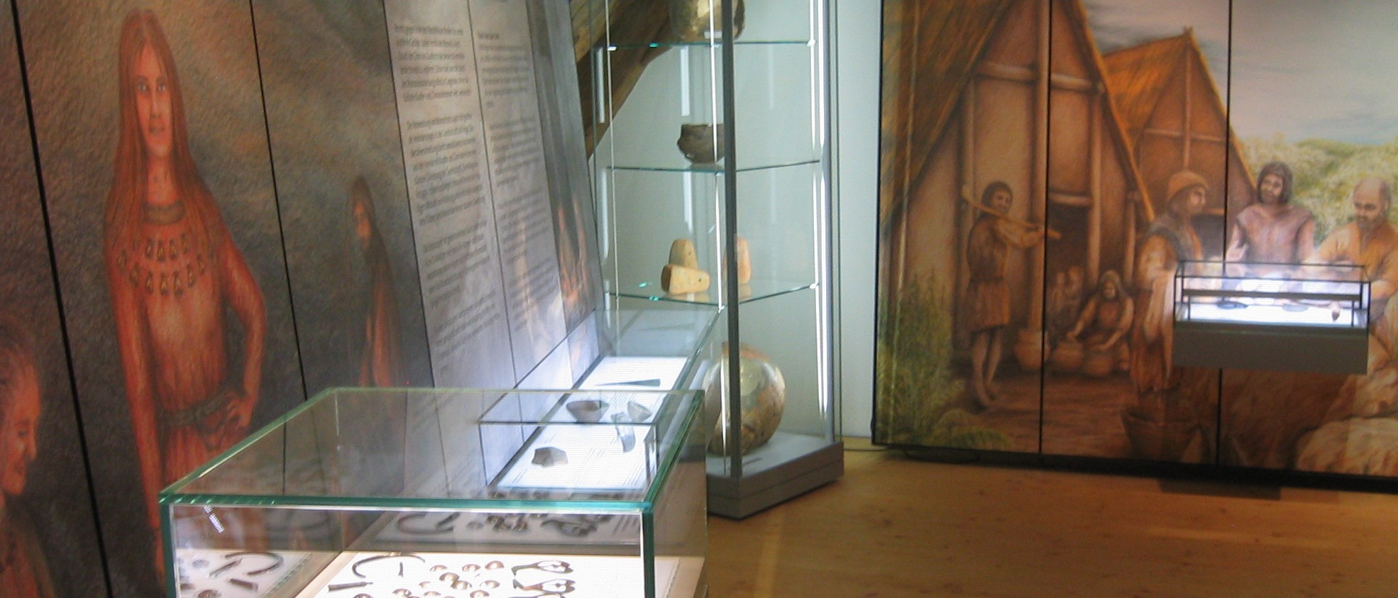 Das Foto zeigt den Blick in die archäologische Dauerausstellung mit Lebensbildern der Bronzezeit und Jungsteinzeit sowie Vitrinen mit entsprechenden Exponaten.