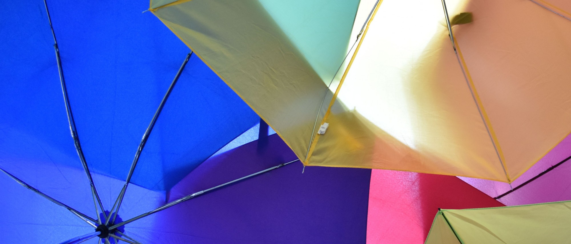 Das Foto zeigt einen Ausschnitt des Ausstellungsplakates &quot;Visionen&quot;. Bunte, aufgespannte Regenschirme bilden ein &quot;Dach&quot;.